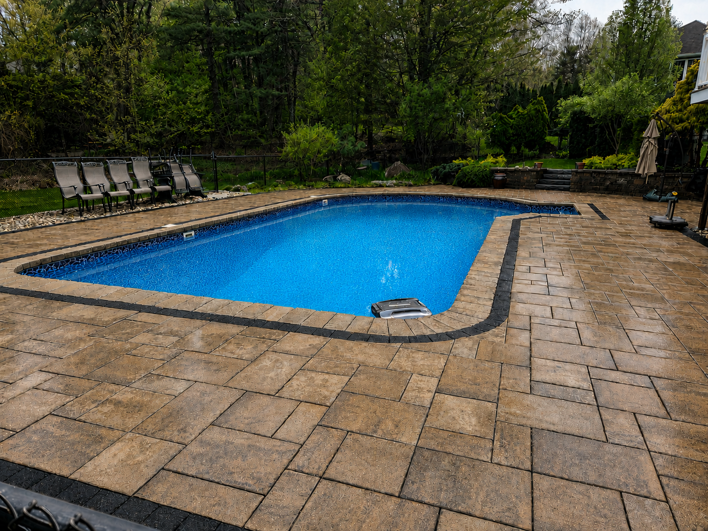 Completed sealed paver pool deck surrounding clean, clear pool water